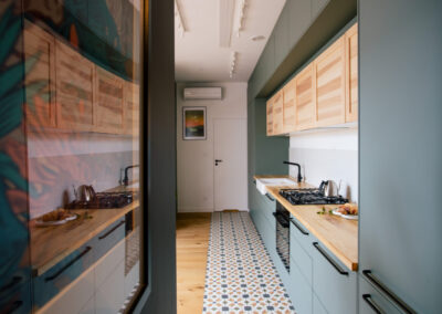Zielona kuchnia widoczna z korytarza z obrazem po lewej